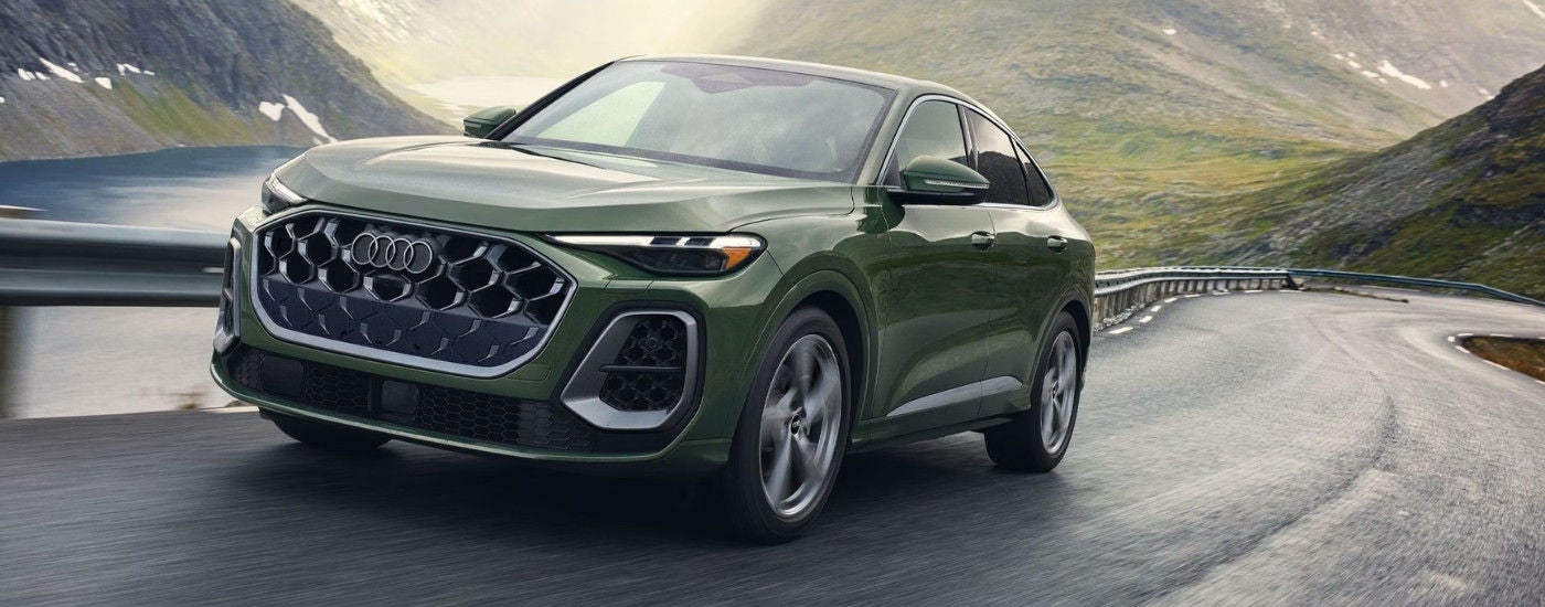 A green 2025 Audi Q5 for sale near Cave Spring driving on a winding road.